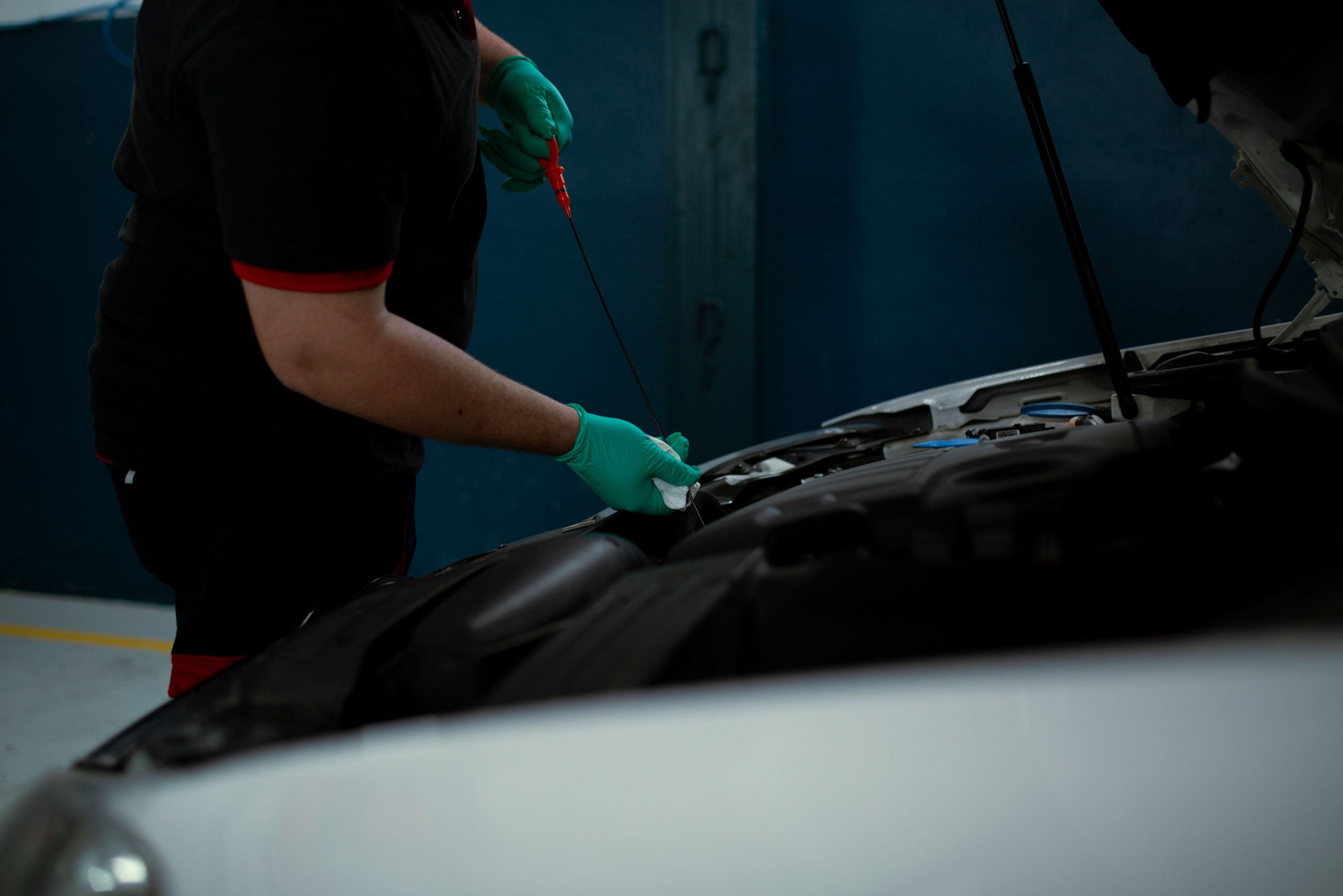 A car repair technician in Bossier City checking oil levels in a vehicle