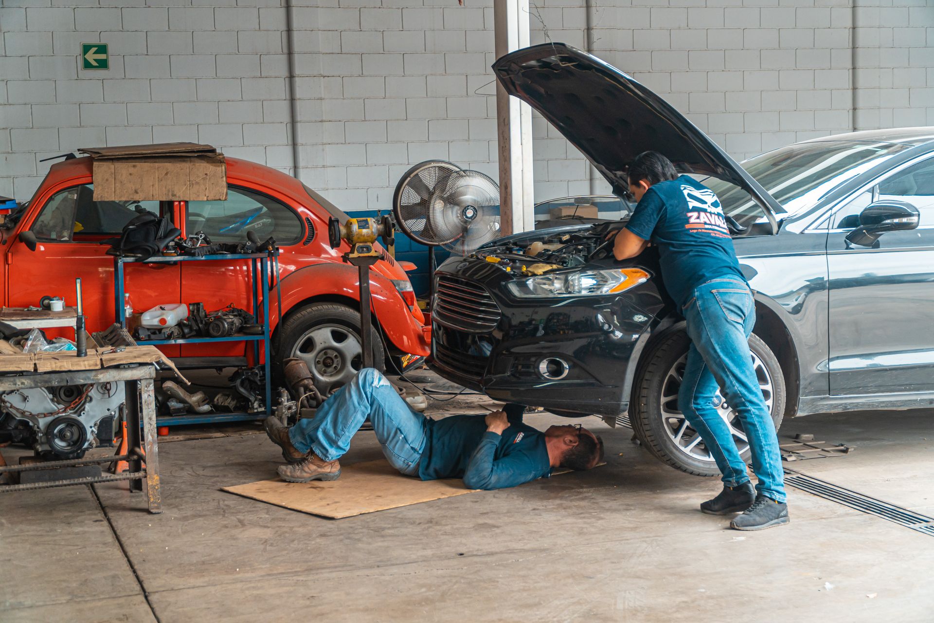 Two car repair shop technicians working on a vehicle in Bossier City
